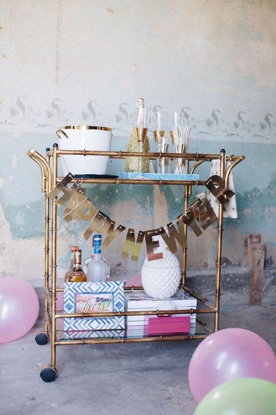 a brass bar cart with a shiny letter garland is all you need for party decor