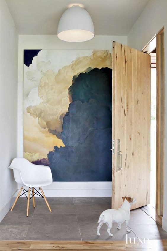 an oversized abtract artwork takes the whole blank wall and makes the entryway interesting