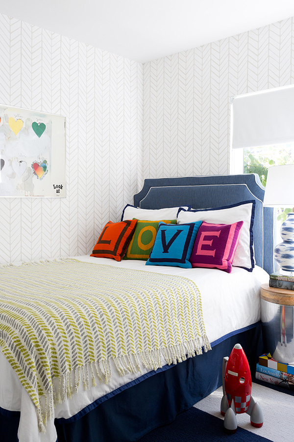 The kids' room is airy and light-colored, and bold shades are brought with pillows