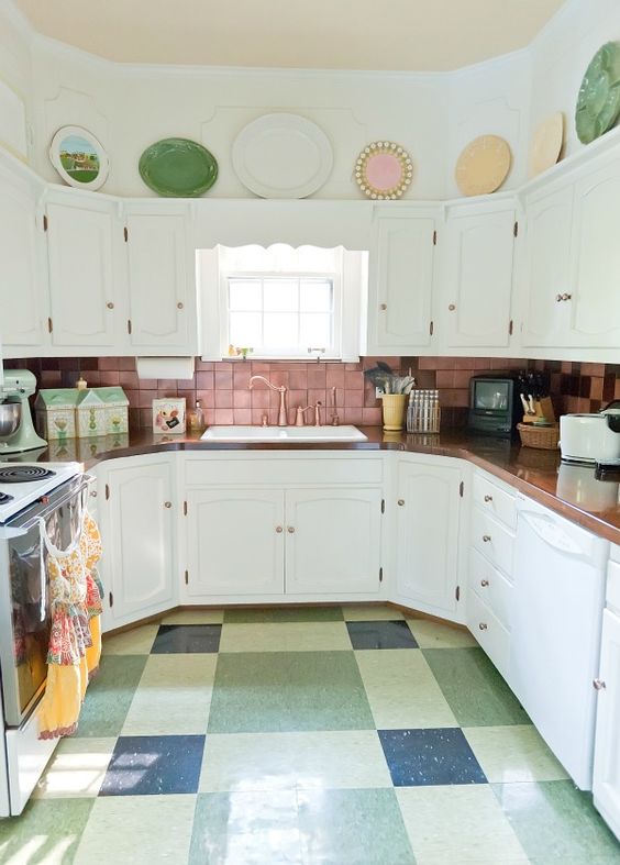 a pink tile backsplash, a colorful tile floor and bold dishes over the cabinets
