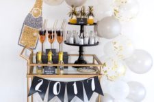 12 a copper bar cart with white and grey balloons, a banner and glitter bottles and glasses