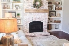 12 a whitewashed red brick fireplace with a wooden mantel for a neutral rustic space