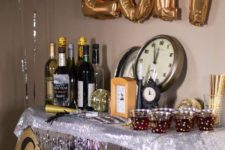 13 a drink station decorated with silver fringe, a glitter garlands, gold balloons and disco balls