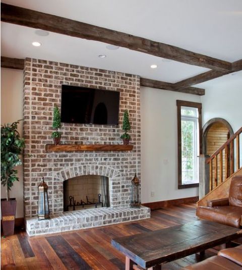 a rustic barn space with a dark yet whitewashed brick fireplace