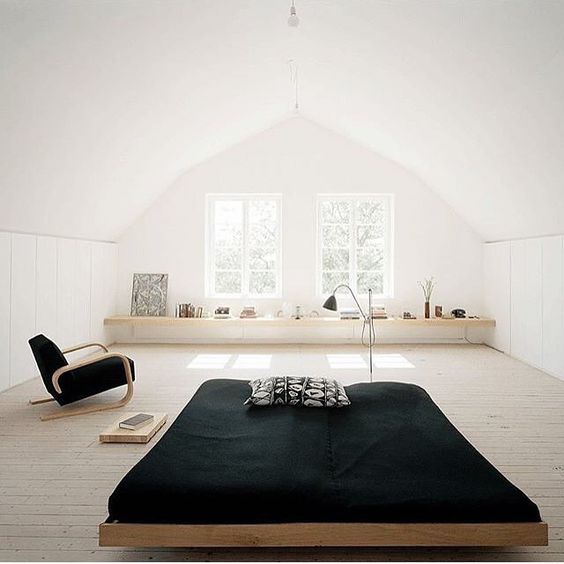 a low Japanese bed and a functional modern chair, black textiles create a contrast