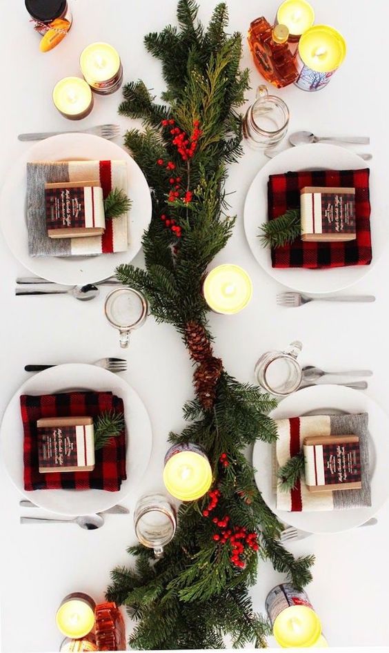 a modern take on a traditional tablescape with plaid, evergreens, pinecones and berries and lots of candles