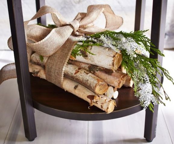 an arrangement of tree branches with greenery and a huge burlap bow