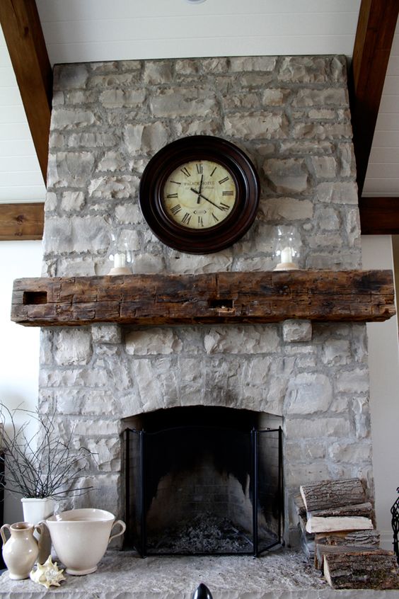 a grey stone fireplace, a reclaimed beam mantel and metal fireplace covers