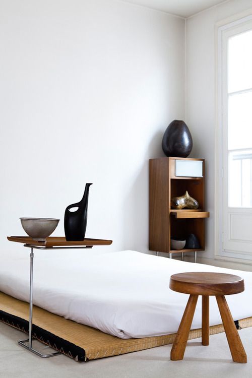 a traditional Japanese bed and some creative wooden furniture that contrasts white walls