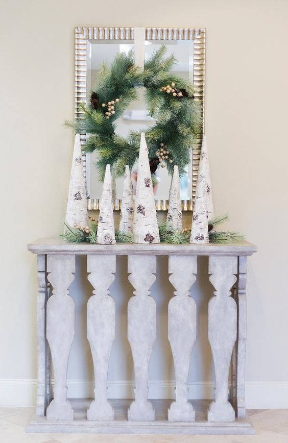 birch bark wrapped cone trees, evergreens and an evergreen wreath on a mirror