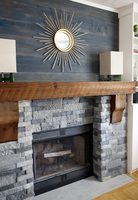 a faux stone clad fireplace with a wooden mantel and dark stained reclaimed wood over the mantel