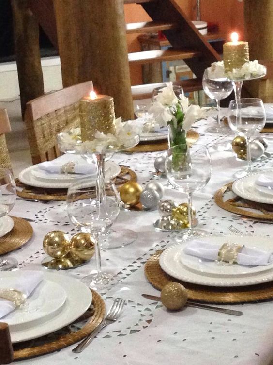 a holiday tablescape with gold and silver ornaments, wicker chargers, glitter candles and white blooms