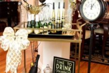 17 a stylish drink bar cart in black and gold with black and gold balloons and a large bow