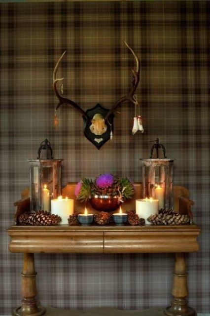 large pinecone, candles an candle lanterns with antlers over the console for a woodland-inspired space