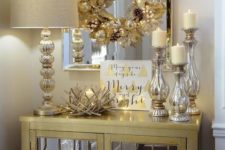 19 a gold wreath with beads and pinecones, mercury glass candle holders and a nest-style candle holder for a glam feel