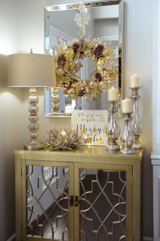 A gold wreath with beads and pinecones, mercury glass candle holders and a nest style candle holder for a glam feel