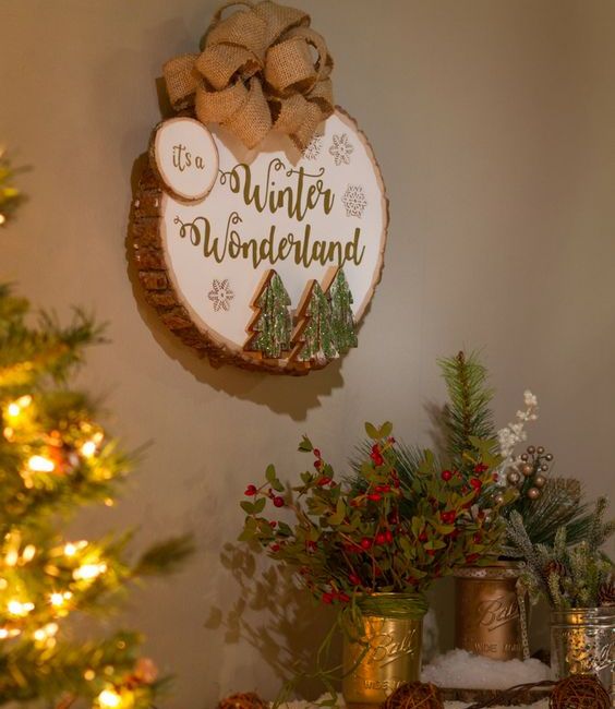 a winter sign with a large burlap bow, Christmas trees attached, snowflakes and calligraphy