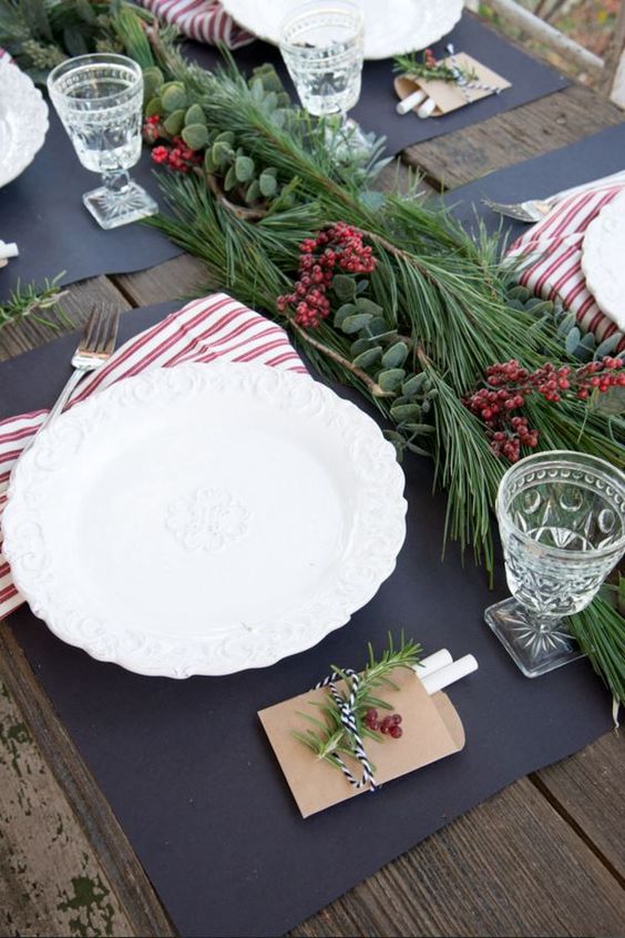 a modern tablescape with an evergreen and berry garland and striped napkins