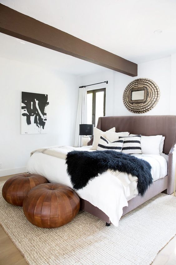 two brown leather round poufs add a Moroccan feel to the bedroom