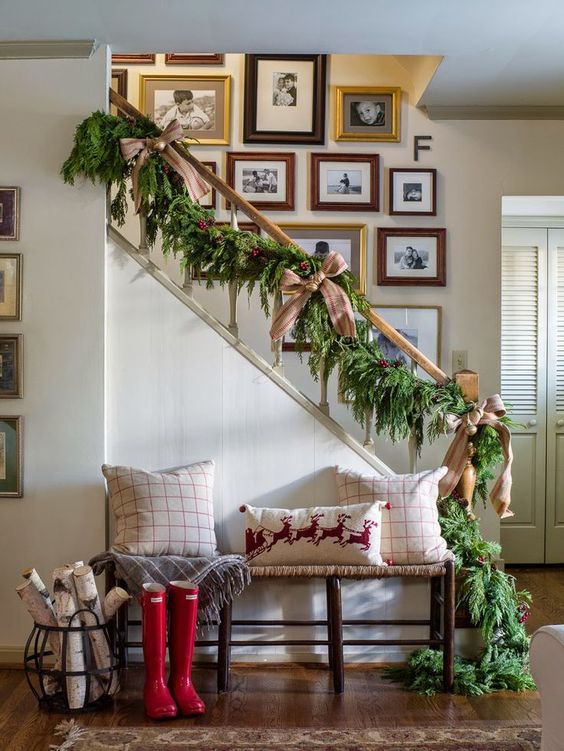 a lush evergreen garland with burlap bows and jingle bells for stairs decor