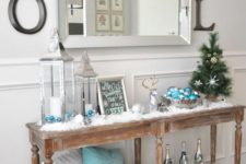 23 a vintage wooden console with faux snow, lanterns, a deer and turquoise touches