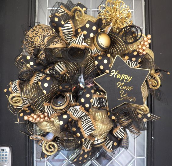 a chic sparkly black and gold wreath with ribbons, ornaments, a chanlkboard star and vignettes