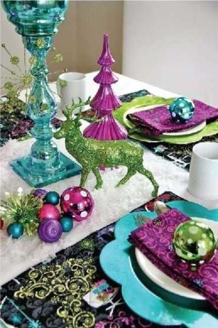 a colorful tablescape with ornaments, napkins and chargers of different colors and a glitter deer