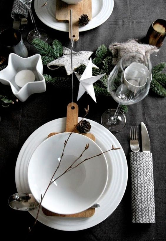 Scandinavian styled table with stars, candles, a knit utensil cover, pinecones and evergreens