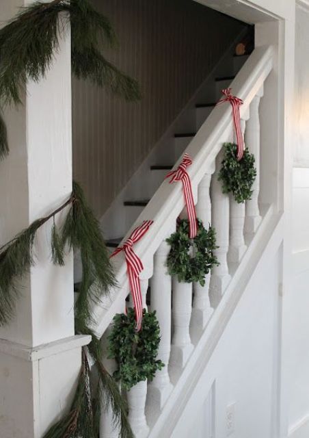 little boxwood wreaths with red and white striped ribbon for staircase decor