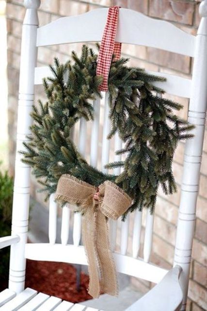 an evergreen wreath with checked ribbon and a burlap bow