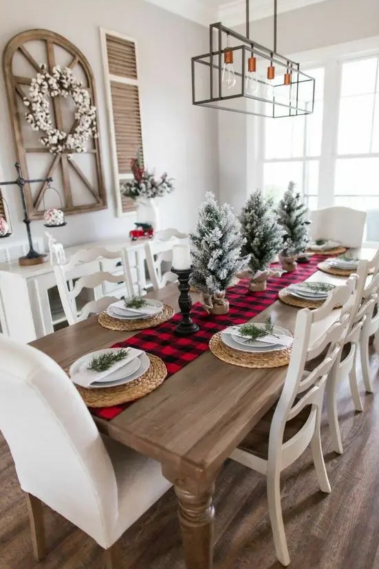 a bright and simple Christmas tablescape with a red plaid table runner, woven placemats, flocked Christmas trees and candles