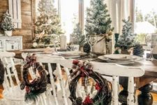 a farmhouse Christmas dining space with whitewashed chairs, snowy Christmas trees and pinecones