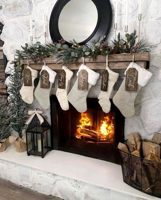 a farmhouse Christmas mantel with evergreens, pinecones, stockings, wooden tags and a candle lantern