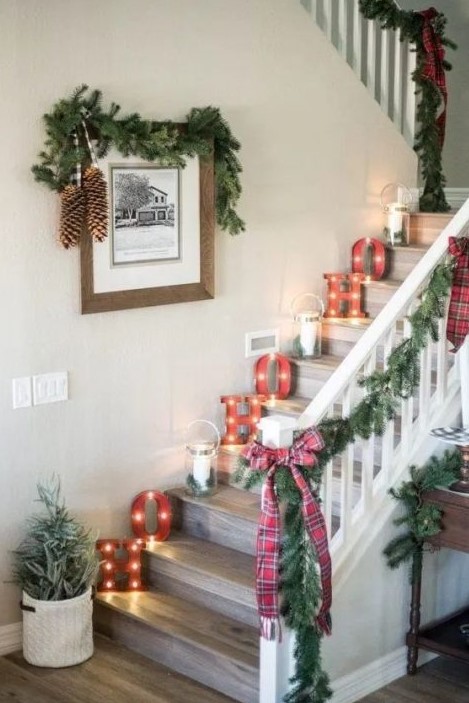 a farmhouse holiday nook with evergreens, plaid bows, pinecones and candle lanterns plus marquee lights