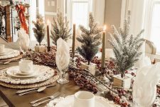 a lovely farmhouse Christmas table setting with woven placemats, white porcelain, mini trees, berries and candles