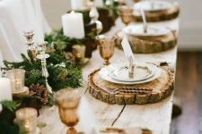 a lush garland with pinecones and candles, wood slice chargers and amber glasses for an elegant rustic tablescape