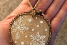 a rustic tree slice Christmas ornament with snowballs and snowflakes is a catchy decor idea
