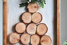 a simple rustic Christmas art of tree slices, greenery and in a wooden frame is a cool and cute decoration