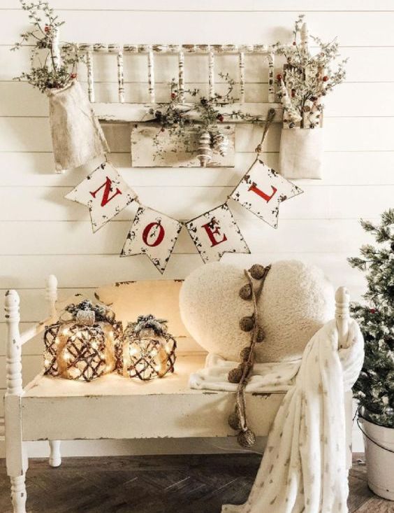 white farmhouse Christmas decor with bunting, candle lanterns, a white heart pillow and some white branches