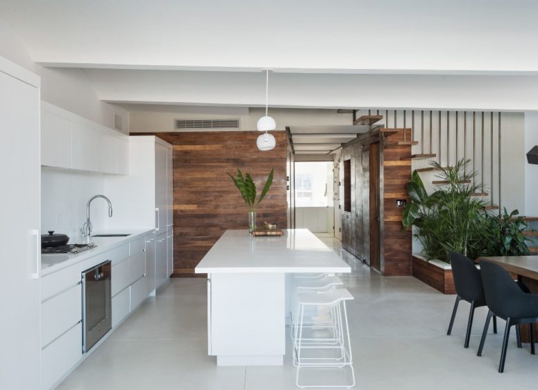 The kitchen is done with white cabinets and a white kitchen island, the wood clad walls create a contrast