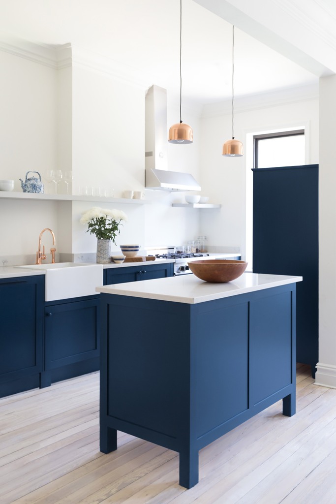 The kitchen was decorated with bold blue cabinets with marble countertops and glam was added with brass and copper touches