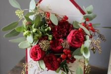 02 a stylish centerpiece of a burgundy lined envelope filled with bold blooms and greenery