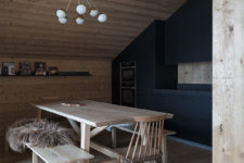 The attic kitchen is done with black metal cabinets, a wooden dining set and some lamps