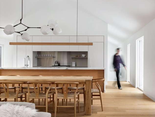 The kitchen features a white cabinets, a marble kitchen island and natural wood, of which the dining set is made too