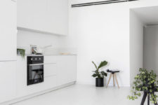 04 The kitchen is done with sleek white cabinets and lots of potted greenery enliven the minimalist space
