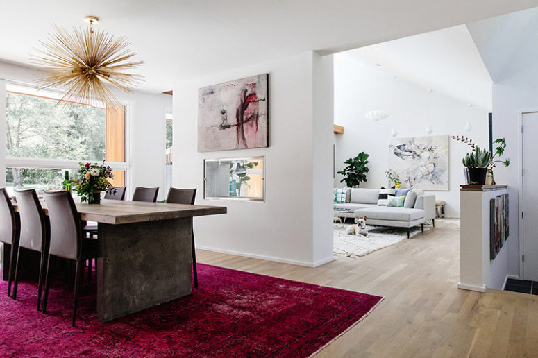The living room is partly divided from the dining room with a fuchsia rug, a bunburst chandelier and a bold artwork