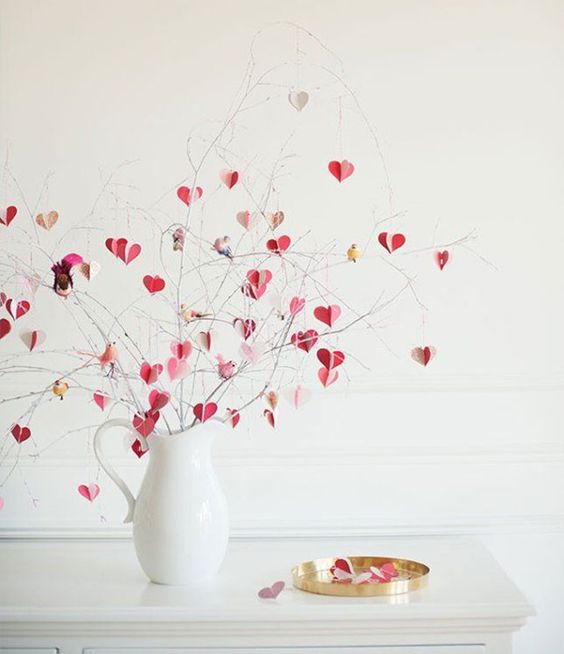 a modern Valentine's Day centerpiece of a white jug and pink, blush and gold hearts on branches