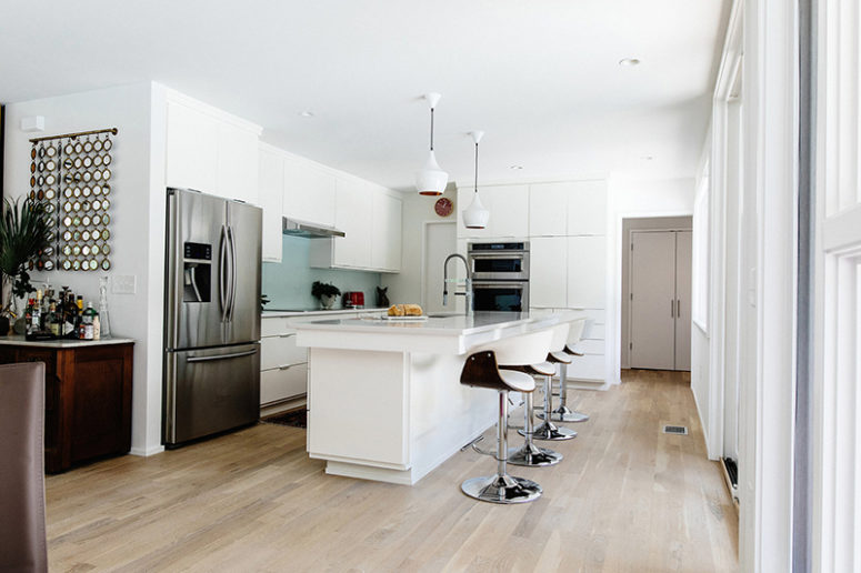 The kitchen with white cabinets and a large kitchen island is only visually separated from the dining room