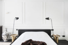 06 The master bedroom is done with white wainscot walls, black furniture and brass nightstands