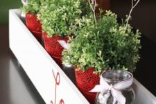 06 a stylish centerpiece in a box with red lace pots, greenery and wire hearts in the pots